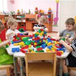 Children sitting at the table, playing with a constructor