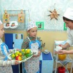 Children in aprons holding a plate with fruit models